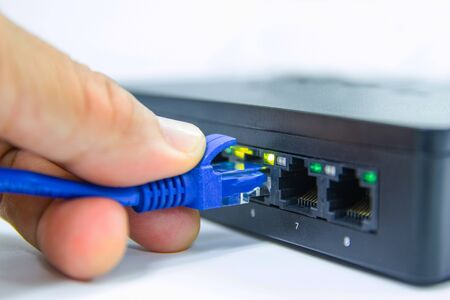 Hand of man holding The network cables to connect Lan port in the Datacenter room, concept...