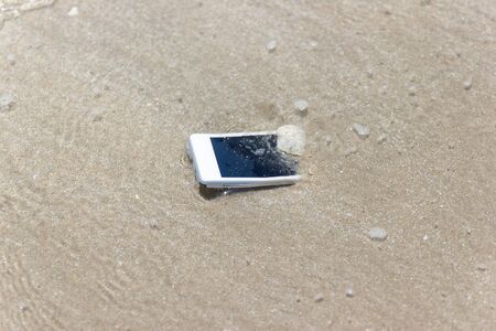 White Mobile phone floated to the sea at the beach.の写真素材