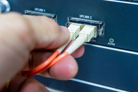 Technician connect fiber cable network to switch port in server room , Concept internet network managementの写真素材