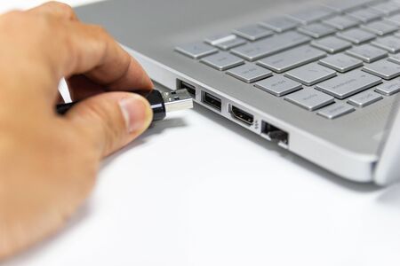 hand man hold Flash drive connect to USB port plug-in computer laptop for transfer data and backup business conceptの写真素材