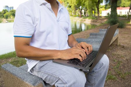 A man is typing on a laptop keyboard works in the park concept Workspace anyware and Remote online work 
の写真素材