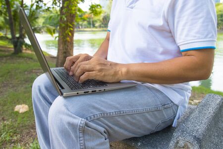 A man is typing on a laptop keyboard works in the park concept Workspace anyware and Remote online work 
の写真素材