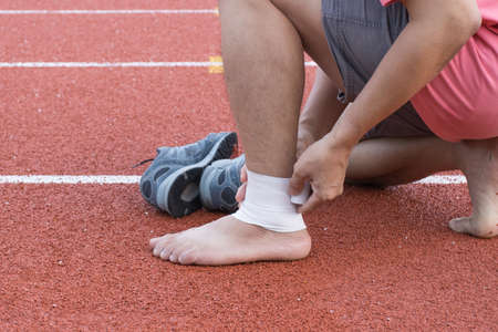 man applying compression bandage onto ankle injury of a football player, Sports injuries, concept...
