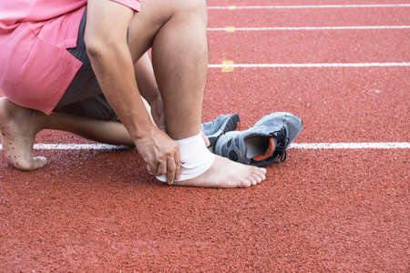 man applying compression bandage onto ankle injury After exercise concept Sports injuries.の写真素材