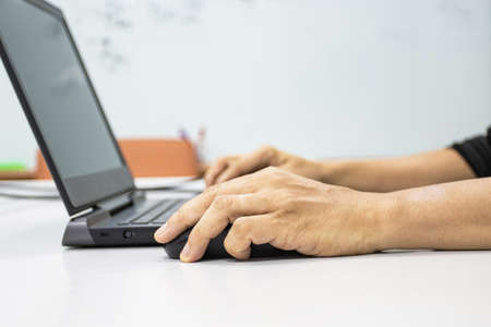 A man sitting using a laptop with hand to hold a mouse show office syndrome concept with weire wrist...