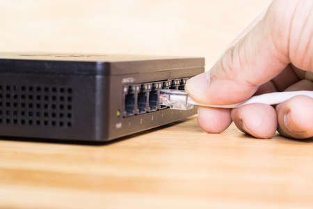 Hand of man holding The network cables to connect Lan port, concept Communication connection technologyの写真素材