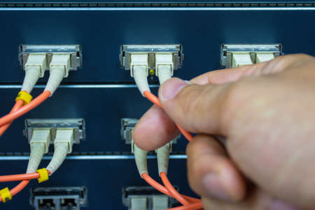 Technician connect fiber cable network to switch port in server room, Concept internet network managementの写真素材
