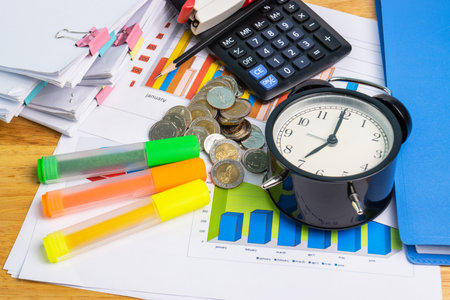 the stack of coin with business paper graphs and pencil with charts report, calculator concept of calculating expenses, incomes and expenses.の写真素材