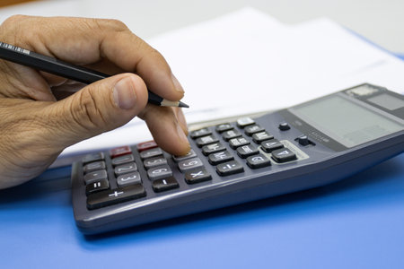 Hand of man use use calculators with documents of income, expenses, concept of life at work.の写真素材