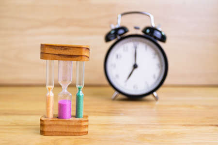 hourglass sand with the clock on a wood table selective focus hourglass