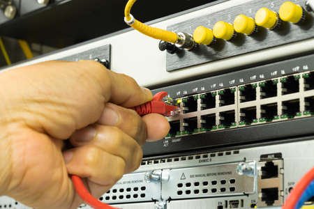 Hand of a man holding The network cables to connect the port of a switch to connect internet...