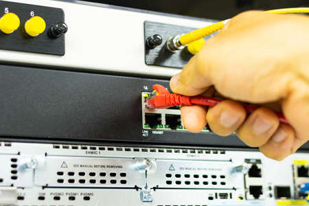 Hand of a man holding The network cables to connect the port of a switch to connect internet network, concept Communication technologyの写真素材