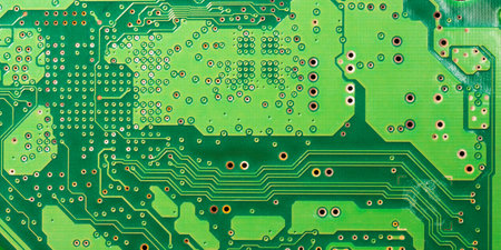 Close-up of a green printed circuit board with electronic components and chips