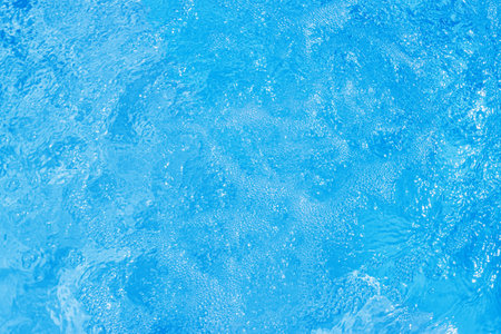 Serene blue water surface with gentle ripples and a soft sun glowの写真素材