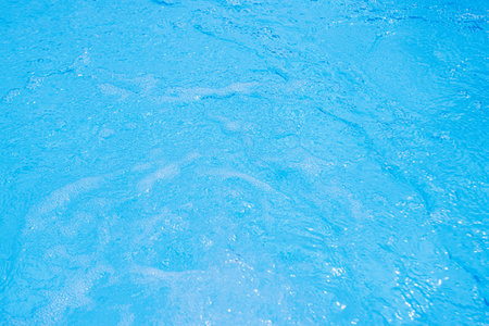 Serene blue water surface with gentle ripples and a soft sun glowの写真素材