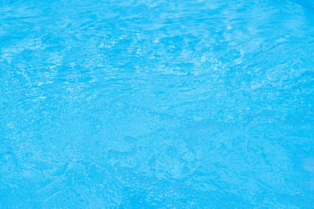 Serene blue water surface with gentle ripples and a soft sun glowの写真素材