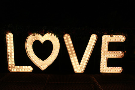 word love from big letters with glowing light bulbs on a dark backgroundの写真素材