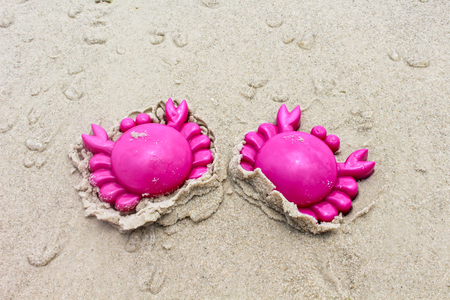 A plastic pink crab sand toy on soft sandの写真素材