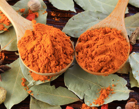 Turmeric powder, crushed herbs on a wooden background.