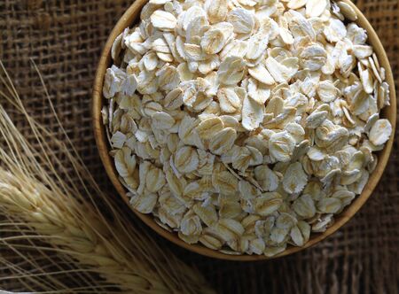 Rolled oats  in a wooden bowl on a sack.