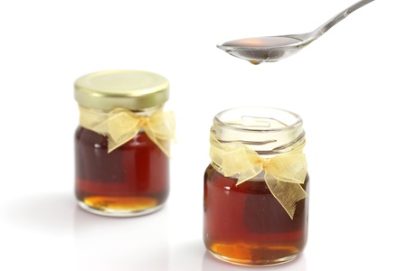 honey dripping from drizzler on top of jar, isolated on white background の写真素材