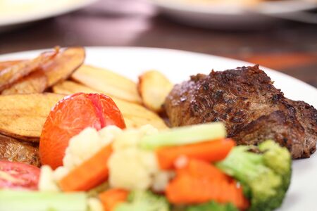 Grilled steak with vegetables on wood backgroundの写真素材