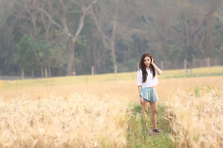 Asian girl on wheat fieldの写真素材