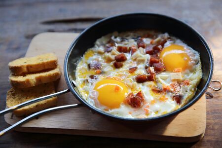 Brealfast fried egg stuff with hot pan with breadの写真素材