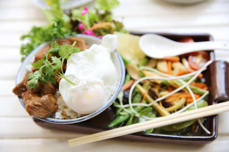 boiled pork roast with rice and egg on wood backgroundの写真素材