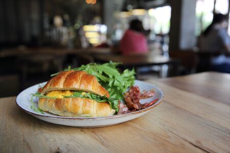 croissant with egg and bacon on wood backgroundの写真素材