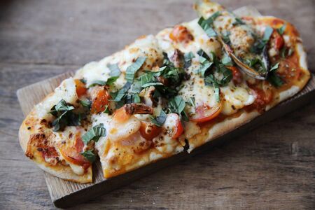 pizza with seafood and tomatoes on a wooden table , italian foodの写真素材