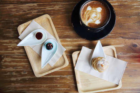 white chocolate with strawberry sauce and hot coffe on wood backgroundの写真素材