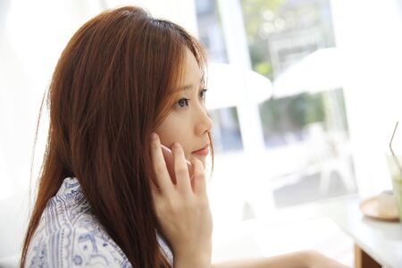 Asian young woman calling talking on phone callephohe in coffeeshopの写真素材