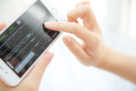 trading online on smartphone with business woman handの写真素材
