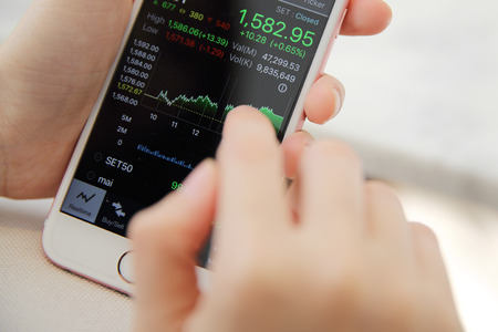 trading online on smartphone with bussiness woman handの写真素材