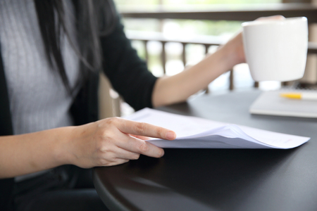 woman hand drinking coffee with business paperの写真素材