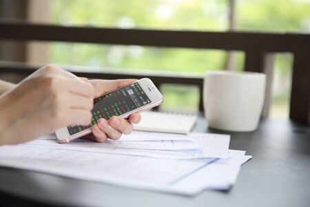 trading online on smartphone with bussiness woman hand and coffeeの写真素材