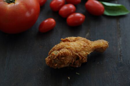 Fried Chicken with tomato in darken wood backgroundの写真素材