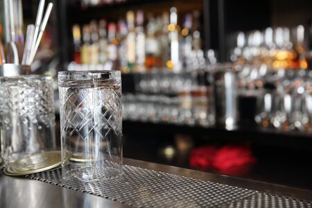 Whiskey glasses on bar counter with blur bottles background