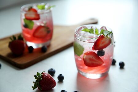 Strawberry juice cocktail with ice and mint on white tone amd woodenの写真素材