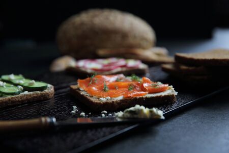 Sandwich with cereals bread smoked salmon beetroot and cucumber on dark marble backgroundの写真素材