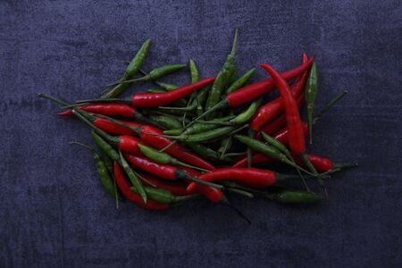Red and green Chili pepper on dark rock backgroundの写真素材