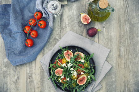 Fresh salad with arugula tomato and cheese on wooden backgroundの写真素材