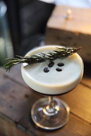 Coffee cocktail with coffee bean and rosemary on top with wood backgroundの写真素材