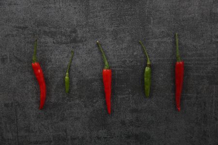 Red and green Chili pepper on dark rock backgroundの写真素材