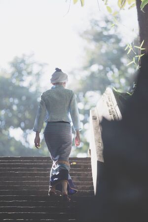 Thai woman wearing traditional Thai dress walk Up the stairs in old thai templeの写真素材