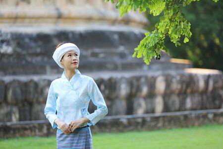 Thai woman wearing traditional Thai dress with old temple background