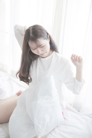 Asian young woman wake up on bed in white toneの写真素材