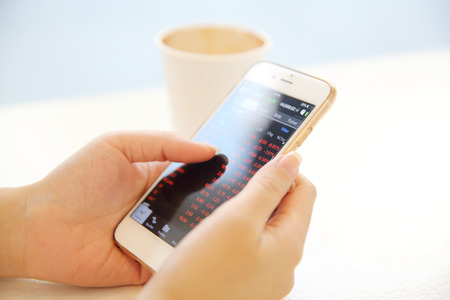 business trading online on smartphone with woman handの写真素材