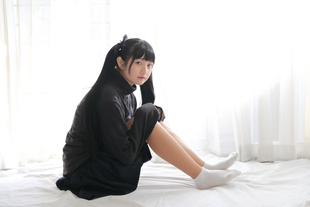 Young pretty girl wearing black cotton sweatshirt on bedroom white toneの写真素材